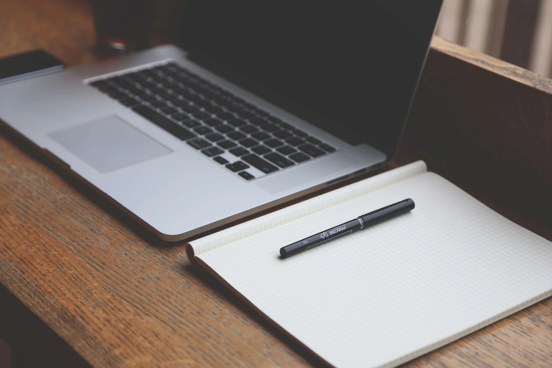 A carefully arranged desk with a laptop and notebook