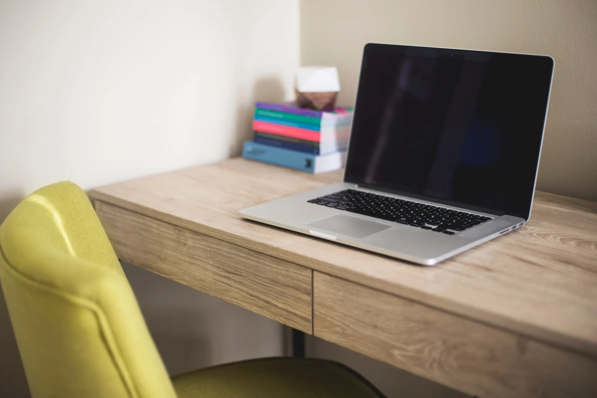 A minimal workspace with a green chair and wooden desk